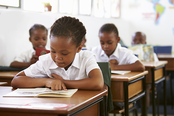 Schoolgirl reading at her desk in elementary school lesson